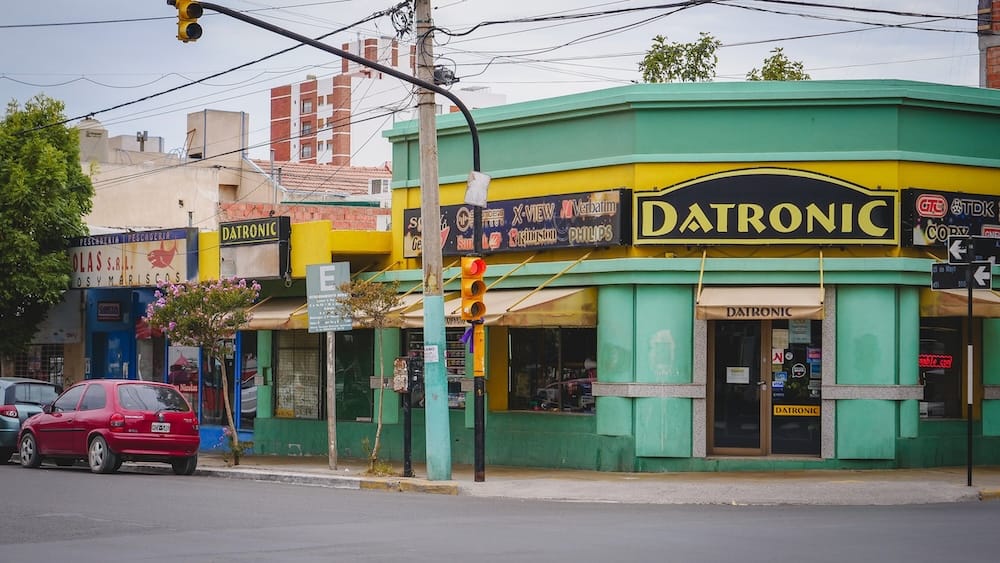 Colorful Commercial Street Corner in Trelew, Chubut, Patagonia, Argentina A colorful commercial street corner in Trelew, Chubut, with local shops, parked cars, overhead wires and traffic lights showing the everyday urban side of Patagonia, Argentina.