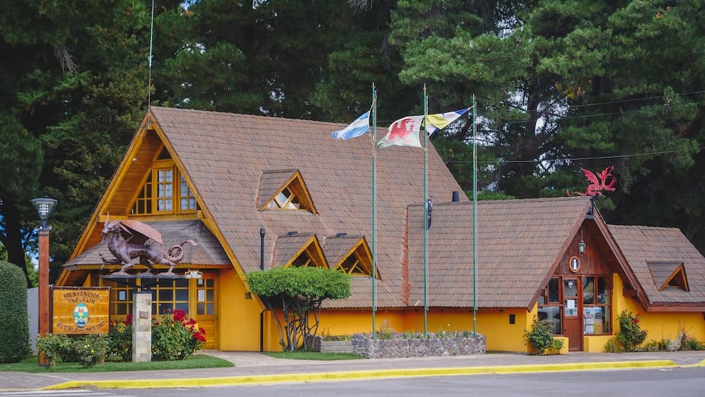 Trevelin Chubut Argentina Welsh and Argentine flags flying above traditional wooden building with dragon symbols, representing the cultural heritage of Y Wladfa and the lasting Welsh identity in Patagonia
