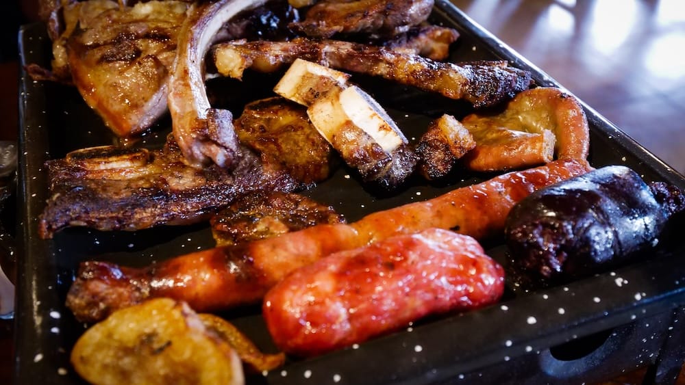 Trevelin Patagonia parrilla at Los Troncos with grilled meats sausages and blood sausage on a hot plate highlighting the hearty Argentine dining options available beyond Welsh tea and desserts in this Andes foothills town