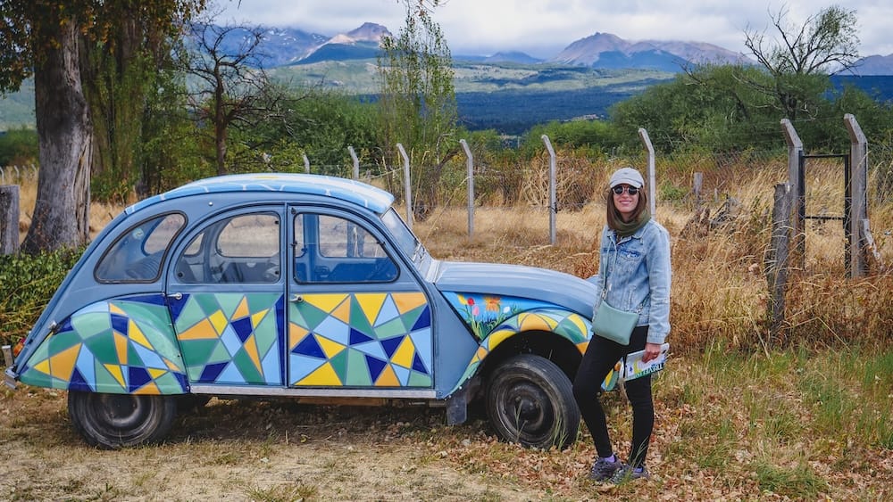 Trevelin Patagonia scene with Audrey Bergner beside a colorful Citroen car, highlighting how even parked vehicles remain exposed to strong Patagonian winds that can impact driving, door handling, and road conditions across the region