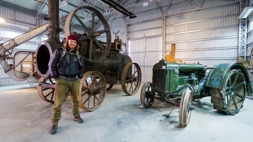 Trevelin Patagonia Samuel Jeffery inside a local museum standing beside historic tractors and farming machinery highlighting Welsh settler heritage and rural history exhibits that add depth beyond tulip season visits