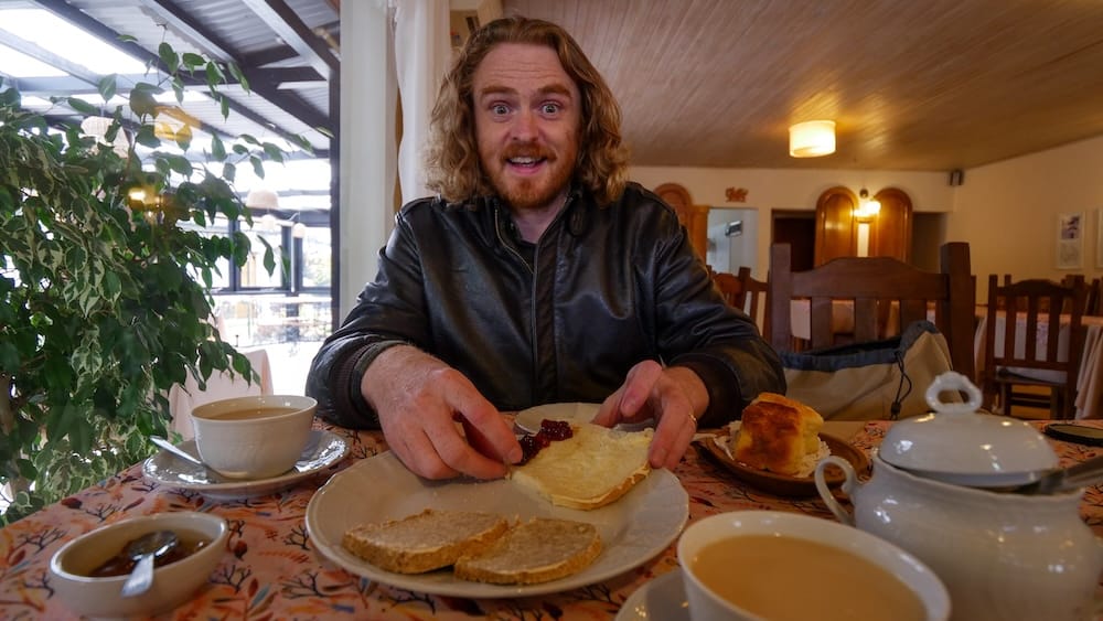 Samuel Jeffery enjoying Welsh tea in Trevelin, Patagonia with bread, jam, and tea service, reflecting how Y Wladfa traditions of communal meals and cultural preservation continue in the Andean settlements far from the original coastal landing sites.
