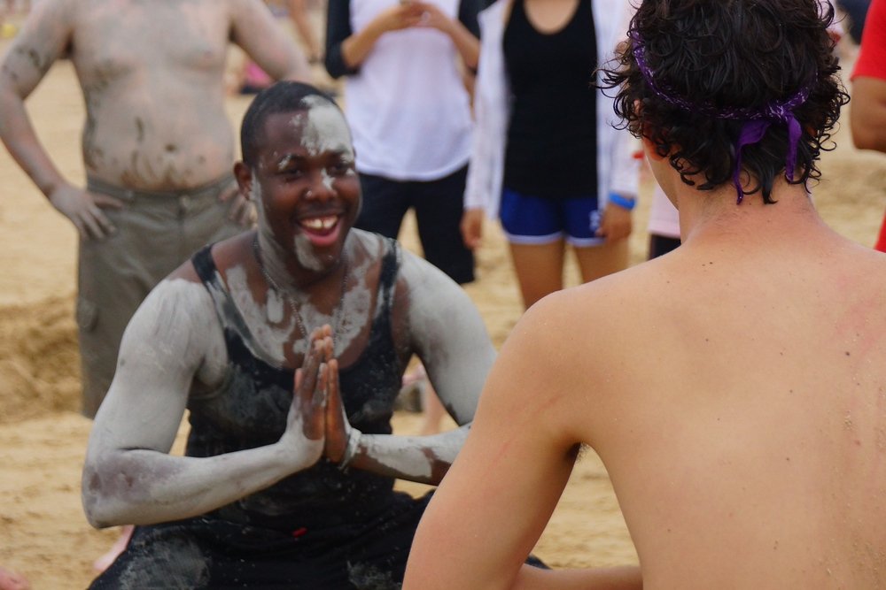 Two foreigners covered in mud engage in a friendly pre-ceremonial ritual before wrestling one another at the Boryeong Mud Festival 