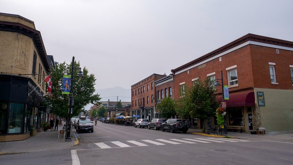 Typical downtown street in Fernie A typical downtown street scene in Fernie, British Columbia, with historic brick buildings, local shops, parked cars, and quiet sidewalks under overcast skies, showing the town’s walkable layout, small-town rhythm, and everyday mountain-community feel.