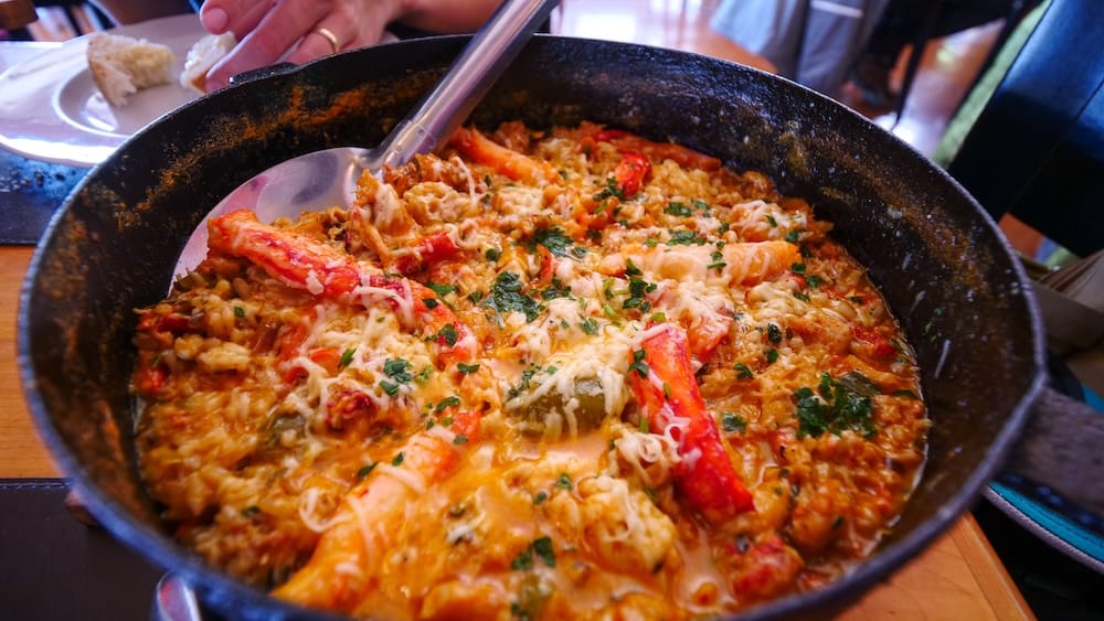 Ushuaia king crab centolla dish in Patagonia showcasing southern seafood dining experience Ushuaia Patagonia Argentina king crab dish with melted cheese and seafood rice in a skillet, showcasing the famous centolla experience in southern Patagonia where portions, presentation, and price can surprise travelers