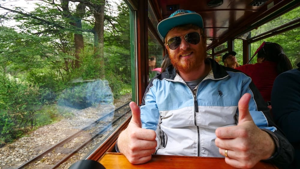 Samuel Jeffery riding the historic Southern Fuegian Railway in Ushuaia Tierra del Fuego Argentina, traveling through dense Patagonian forest while showcasing one of the region’s most accessible and scenic experiences near the end of the world.