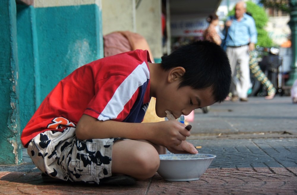 Vietnamese boy slurping pho street level view in Vietnam 