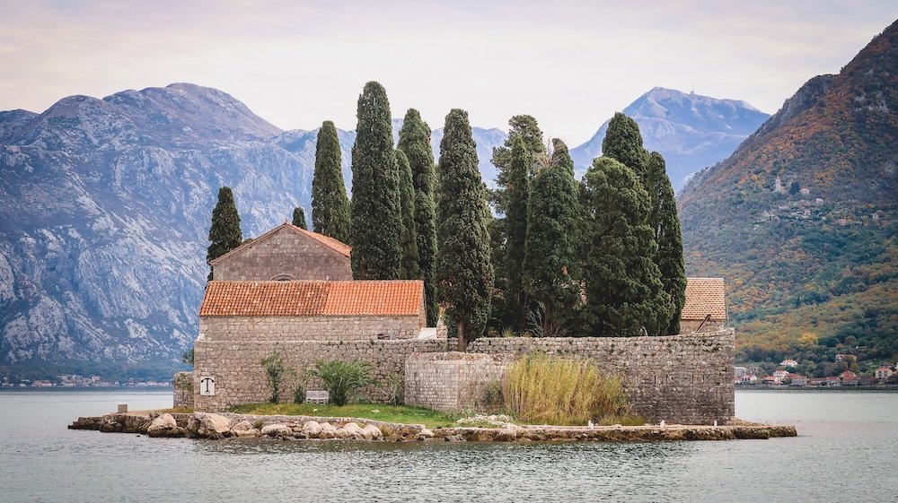 Views of Island of Saint George Ostrvo Sveti Dorde from out boat tour including cypress trees and a Benedictine monastery on our Perast day trip in Montenegro