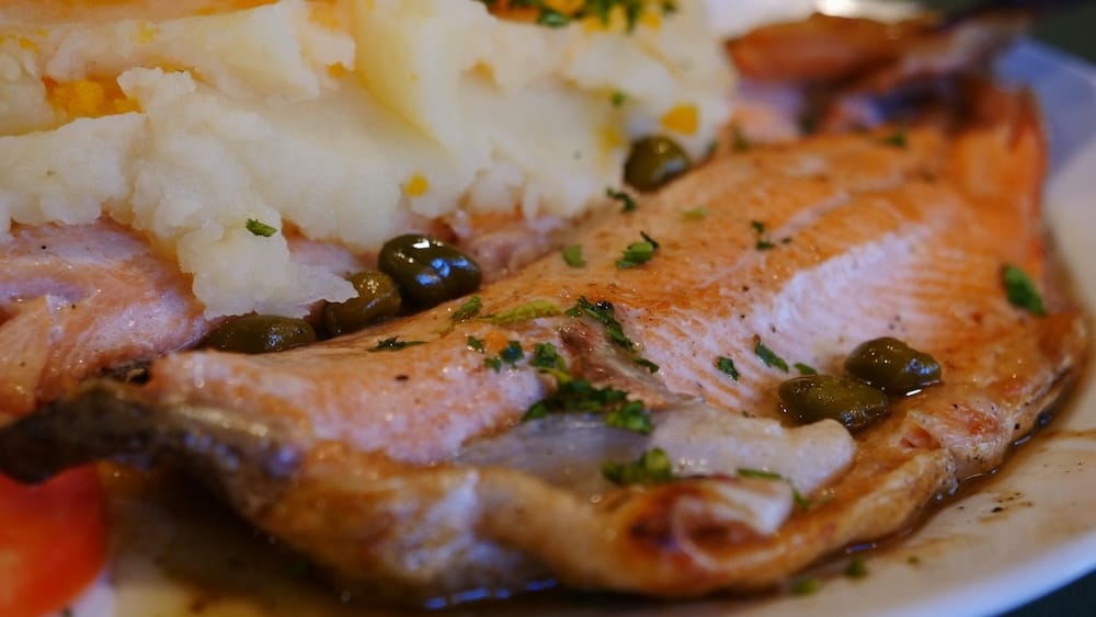 Villa La Angostura trout dish in Patagonia showcasing lakes region freshwater fish cuisine Villa La Angostura Patagonia Argentina trout dish with mashed potatoes and capers, highlighting freshwater fish cuisine in the Andean lakes region where European influences and lighter meals define northern Patagonia food culture