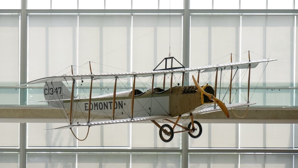 Biplano antiguo "Edmonton" (C1347) suspendido en el atrio, Royal Alberta Museum, Edmonton, Alberta, Canadá Un biplano antiguo marcado como "Edmonton" y registrado como C1347 cuelga suspendido en un atrio con paredes de vidrio en el Royal Alberta Museum en el centro de Edmonton, Alberta, Canadá, con su hélice de madera y alas con soportes de alambre visibles contra los ventanales altos.