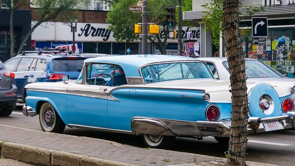 Vintage Ford Galaxie on Whyte Avenue in Old Strathcona, Edmonton, Alberta, Canada, urban street view Blue-and-white vintage Ford Galaxie parked in traffic on Whyte Avenue, with storefronts, street signs and other vehicles surrounding it in Old Strathcona, Edmonton, Alberta, Canada.