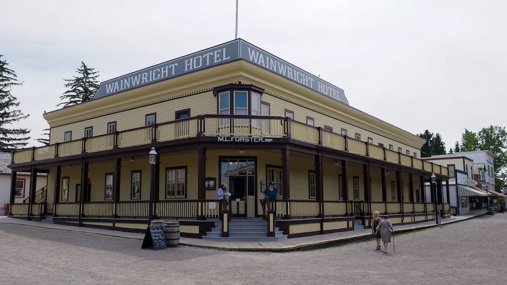 Wainwright Hotel on a historic street inside Heritage Park Historical Village in Calgary, Alberta, Canada, with its wraparound veranda and period storefronts nearby.