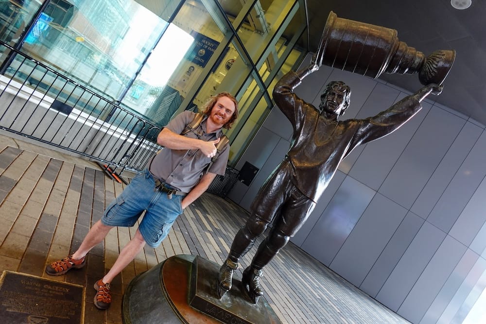 Estatua de Wayne Gretzky en el centro de Edmonton, Alberta, Canadá, junto a Samuel Jeffery Samuel Jeffery hace pulgar arriba junto a la estatua de bronce de Wayne Gretzky en el centro de Edmonton, Alberta, Canadá, mientras la figura del astro del hockey sostiene la Stanley Cup sobre la cabeza.