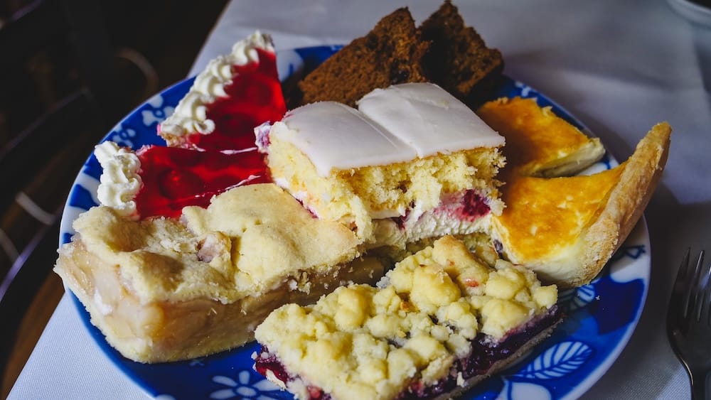 Assorted Welsh cakes and desserts in Gaiman Patagonia including torta negra, sponge cake, fruit tart, and crumb cake served as part of the traditional multi-tier Welsh tea service known for its massive portions and rich flavors