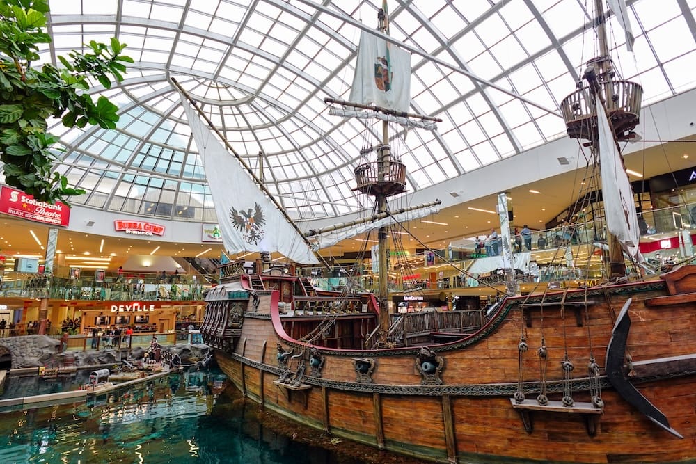 Pirate Ship and Indoor Lake at West Edmonton Mall in Edmonton, Alberta Full-size replica pirate ship beside the indoor lake at West Edmonton Mall in Edmonton, Alberta, beneath the mall’s glass atrium roof and surrounding shops.