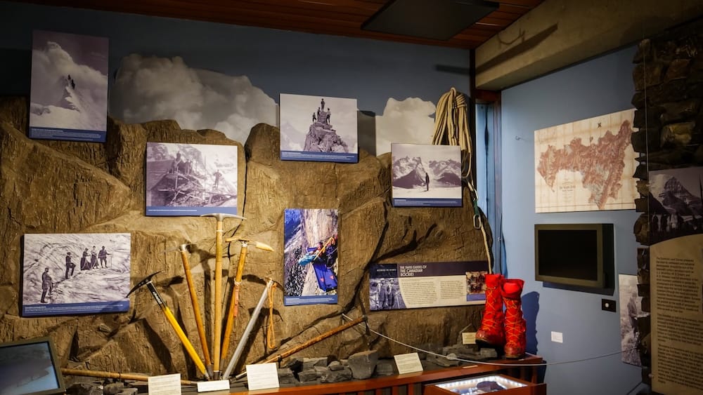 Mountaineering history display inside The Whyte Museum in Banff, Alberta, Canada, with historic climbing photographs, ice axes, rope, boots and Rocky Mountain expedition interpretation.