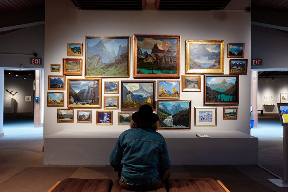 Founders Gallery landscape paintings, Whyte Museum of the Canadian Rockies, Banff, Alberta Samuel Jeffery sits facing a densely hung wall of gold-framed mountain and lake landscape paintings in the Founders Gallery at the Whyte Museum of the Canadian Rockies, Banff, Alberta, Canada.