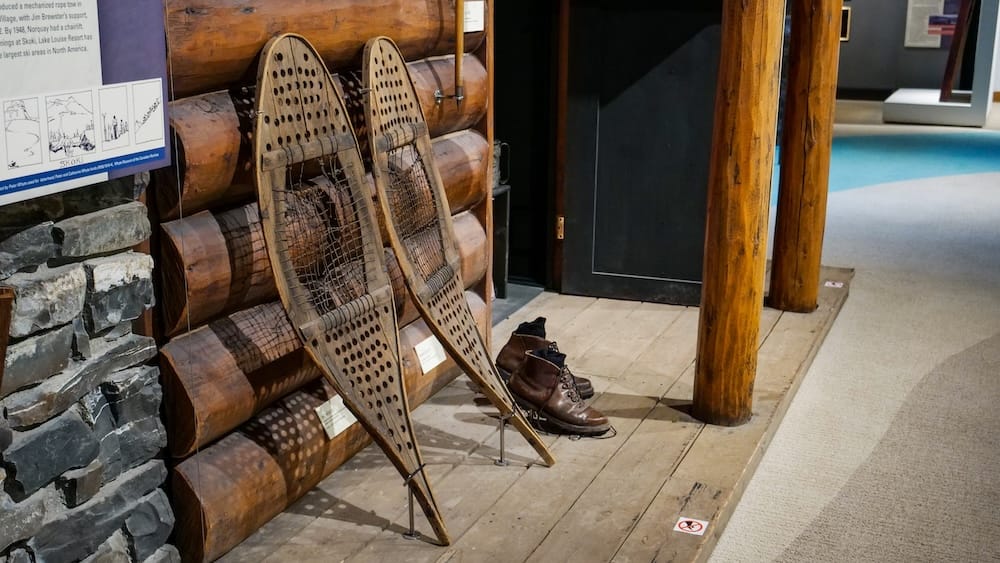 Vintage snowshoes and hiking boots, Heritage Gallery, Whyte Museum of the Canadian Rockies, Banff A pair of wooden-framed vintage snowshoes and worn leather hiking boots displayed against a log wall in the Heritage Gallery at the Whyte Museum of the Canadian Rockies, Banff, Alberta, Canada.