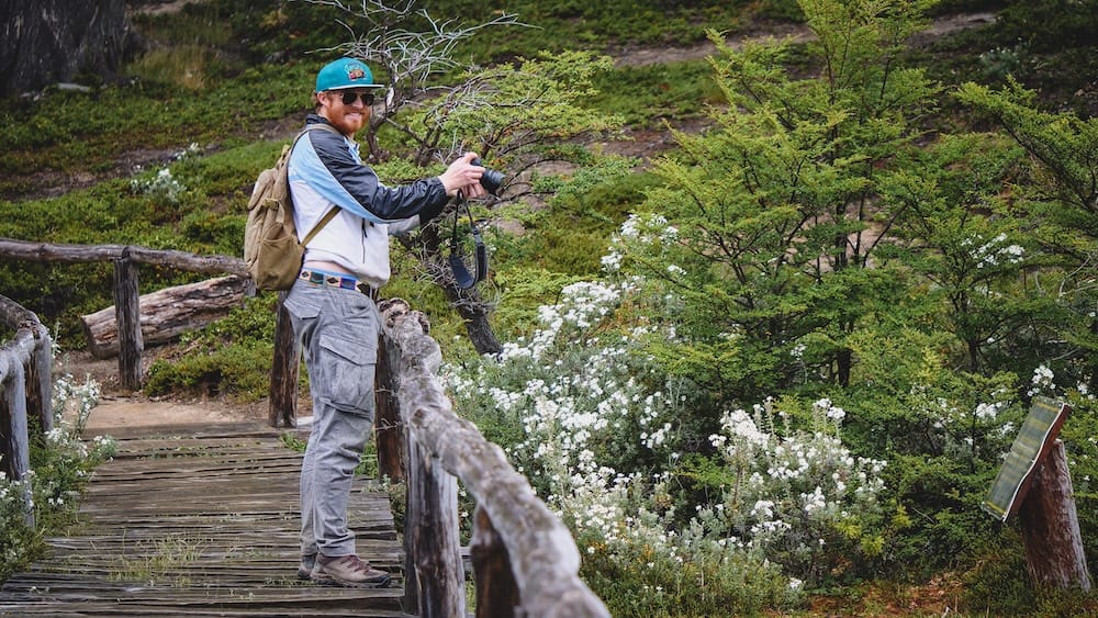 Wild Flora Boardwalk in Tierra del Fuego National Park Ushuaia for Patagonia Summer Trail Access, Samuel Jeffery Samuel Jeffery photographing wild flora from a wooden boardwalk in Tierra del Fuego National Park near Ushuaia, showing how summer access can make Patagonia’s far southern trails easier for nature walks, photography and slower forest exploring.